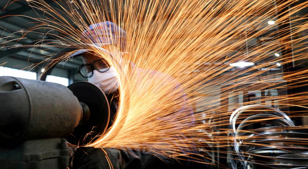 A worker wearing a face mask works on a production line manufacturing bicycle steel rim at a factory