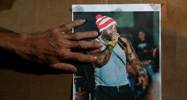 The hand of a Cuban woman is seen next to a picture of late reggaeton singer Jose Manuel Carbajal E