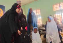 Katsina State Commissioner of Education Zainab Musawa presenting the leaning material to a student d