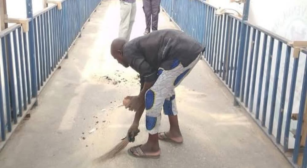 One of the hoodlums cleaning faeces while officials of the Lagos State Ministry of Environment watch